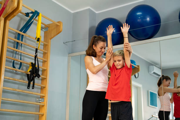 un enseignant aide un enfant en classe d’éducation physique - sports, educational enrichment and development of core skills photos et images de collection
