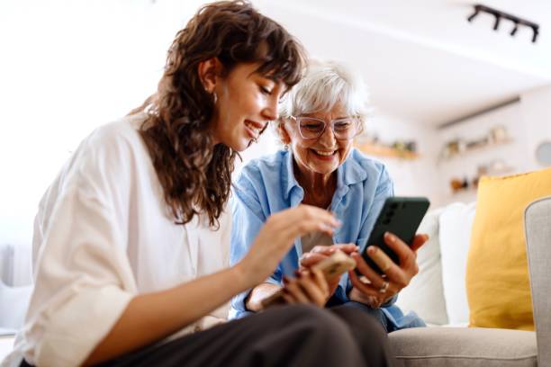 close-up of a volunteer teaching a senior woman how to use a smartphone - elderly support services photos et images de collection