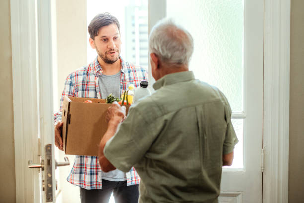 jeune homme livrant des courses à un propriétaire âgé - elderly support services photos et images de collection