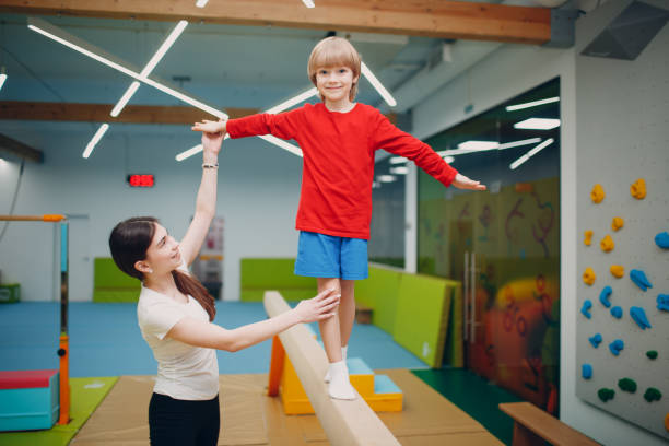 gosses faisant des exercices de gymnastique de faisceau d’équilibre dans la gymnastique à la maternelle ou à l’école primaire. concept de sport et de forme physique pour enfants. - sports, educational enrichment and development of core skills photos et images de collection